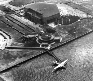 Aerial view of Marine Air Terminal a Pan Am Boeing 314 Clipper in the water next to loading ramp. First Flight to Europe 3 30 1940 Metropolitan Airport News