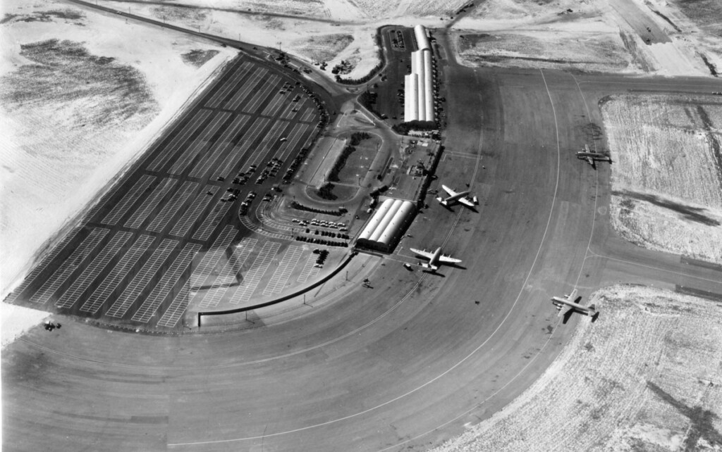 Aerial view of temporary terminal building and parking lot with four-aircraft-on-ramp. Two Lockheed Constellations and Douglas DC-4's. (1948)