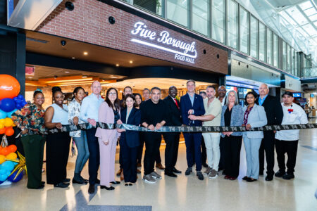 SSP America and JFKIAT Celebrate the Next Chapter of Five Borough Food Hall at Terminal 4 SSP America, a division of SSP Group, a leading operator of food and beverage brands in travel locations worldwide, together with JFKIAT, the operator of Terminal 4 at John F. Kennedy International Airport, today announced the reopening of the refreshed Five Borough Food Hall, SSP America’s proprietary New York-inspired food hall concept at JFK Terminal 4. The reopening was celebrated with a ribbon cutting at Terminal 4 on May 21, bringing together representatives from JFKIAT, SSP America, For Five Coffee Roasters, joint venture partners, airport leaders, and the teams behind the refreshed dining experience. Since its debut, Five Borough Food Hall has been recognized as one of SSP America’s signature proprietary concepts, earning AXN’s Best New Concept award in 2018 and FAB Awards’ Airport Street Food Offer of the Year in 2018. Originally created by SSP America in partnership with JFKIAT, Five Borough Food Hall has been reimagined for today’s traveler while preserving the energy, variety, and unmistakable New York spirit that made the concept a standout at Terminal 4. The refreshed food hall brings together a broad all-day lineup including For Five Coffee Roasters, Dromos Fresh Greek Food, Mango Taco Truck, Five Borough Food Hall Deli, and 5BFH Pizza, offering travelers everything from locally roasted coffee and pastries to Greek-inspired bowls, tacos, burritos, New York deli sandwiches, pizza, salads, and grab-and-go items. As the international terminal of JFK, Terminal 4 is where America greets the world — and where Big City dining starts before the journey begins. Today, Terminal 4 spans more than two million square feet, serves more than 27 million passengers annually, houses 21 airlines, and supports a community of 12,000 employees. In a terminal defined by movement, diversity, and global connection, Five Borough Food Hall offers a dining experience designed to meet the moment: fast when travelers need speed, varied when they want choice, and unmistakably rooted in New York. The refreshed design moves the original concept forward from its food-truck hall roots into a modern New York neighborhood market. Warm wood details, brick textures, mural-wrapped columns, subway-inspired tile, bold menu graphics, branded refrigerated cases, and open service counters create a layered sense of place that nods to the streets, storefronts, delis, slice shops, coffee counters, and global flavors found across the five boroughs. “Five Borough Food Hall has always captured what makes New York such an extraordinary food city: its pace, diversity, and creativity,” said George Mboya, CEO of SSP America. “This refresh marks an exciting new chapter for a concept created specifically for JFK Terminal 4 and a key part of our partnership with JFKIAT. Together, we’re continuing to deliver authentic dining experiences that reflect the city outside the terminal and bring the best part of the journey to life for our travelers.” “Marking the reopening of Five Borough Food Hall at JFK T4 is a significant milestone as we continue to elevate the terminal experience for our passengers,” said Roel Huinink, Chief Executive Officer of JFKIAT. “Thanks to our long-lasting partnership with SSP America, who have been instrumental throughout our 25-year journey, passengers at T4 will have access to a curated selection of exceptional culinary options, offering a New York sense of place that aligns with the Port Authority’s vision for JFK. The addition of For Five Coffee Roasters exemplifies that vision, and we’re very pleased that this local Queens-based business will have the opportunity to enter the airport concessions space for the first time with the benefit of SSP’s global expertise and mentorship.” A key part of the refreshed offer is the addition of For Five Coffee Roasters, the Queens-born specialty coffee company known for small-batch roasting, premium beans, and cafés designed around craft, hospitality, and New York energy. Its Five Borough Food Hall menu includes hot and iced espresso drinks, cold brew, matcha, chai, pastries, and signature beverages including The Five and The Louie. "Opening our first airport location at JFK is a milestone that feels especially meaningful because it brings us back to where our story began — Queens,” said Stefanos Vouvoudakis, Co-Founder and CEO of For Five Coffee Roasters. “For Five was built to redefine what coffee hospitality could look like — combining elevated design, exceptional product, and a level of service that delivers a luxury experience within an everyday ritual. To now bring that vision to one of the world’s most iconic gateways is an exciting milestone for our team and our brand. Through our partnership with SSP America and JFKIAT, we’re proud to introduce travelers from around the world to a New York-born coffee experience rooted in craftsmanship, hospitality, and the energy that defines this city.” The refreshed Five Borough Food Hall also supports the operational realities of one of North America’s busiest international terminals. Multiple counters, clear menu identities, strong visual cues, grab-and-go merchandising, and a broad range of meal solutions help serve different passenger needs across the day — from early morning coffee and breakfast to lunch, dinner, snacks, and meals to take to the gate. The reopening comes as JFK Terminal 4 celebrates its 25th anniversary, marking a milestone year for one of the most significant public-private aviation partnerships in the United States. SSP America’s presence at Terminal 4 is part of a longstanding relationship with JFKIAT, built around a shared commitment to delivering a food and beverage program that matches the caliber, complexity, and international character of the terminal. SSP America and JFKIAT Celebrate the Next New Chapter of Five Borough Food Hall at JFK Terminal 4
